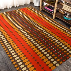 an orange and brown rug on the floor in front of a book shelf with books