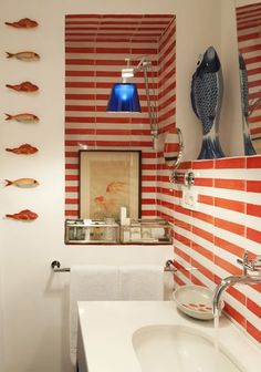 a bathroom with red and white stripes on the wall next to a sink in front of a mirror