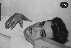 black and white photograph of a man laying in bed with his hand on the pillow