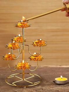 a candle holder with four candles on it and a hand holding the candle in front of it