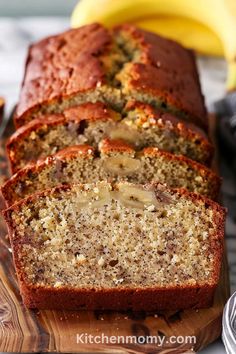 slices of banana bread on a cutting board with bananas in the back ground and another sliced loaf next to it