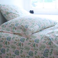 an unmade bed with floral sheets and pillows