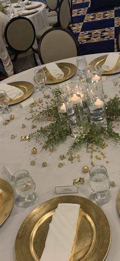 the table is set with gold plates and place settings