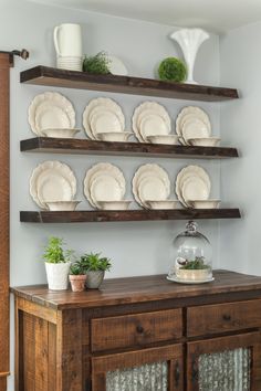 a wooden table topped with lots of plates and bowls on top of shelves next to a potted plant