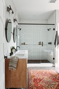 a bathroom with a rug, sink and shower stall in it's center area