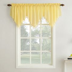 a window with yellow sheer curtains hanging from it's side