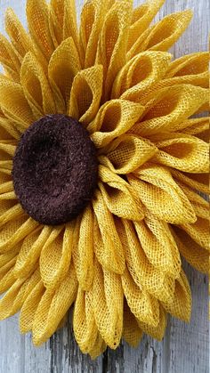 a close up of a yellow and brown flower on a wooden surface with text that reads, how to make a sunflower out of yarn