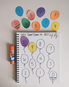 a spiral notebook with numbers and balloons on it, next to an orange marker that says let's count down to 2012