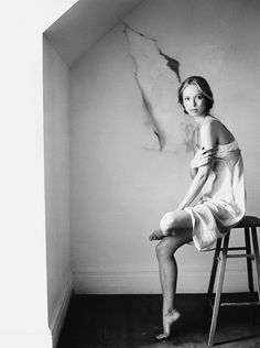 a black and white photo of a woman sitting on a stool