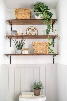 some shelves with plants and baskets on top of them in a white toilet bowl next to a wooden wall