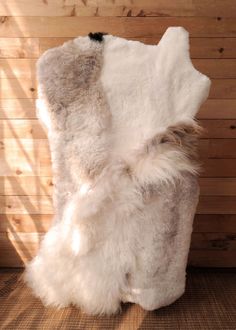 the back end of a sheepskin chair with fur on it's sides and wood planks in the background