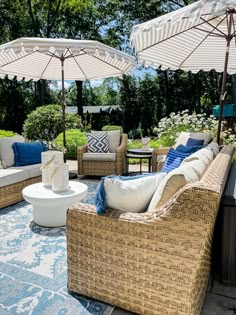 an outdoor living area with wicker furniture and umbrellas over the couches,