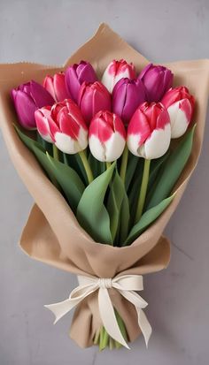 a bouquet of pink and white tulips wrapped in brown paper