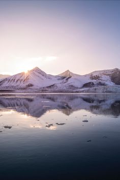 the mountains are covered in snow as the sun is setting over the mountain range behind them