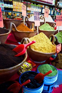 several bowls filled with different colored powders on display at a market stall in india