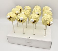 there are many yellow cake pops with white frosting and honeybees on them