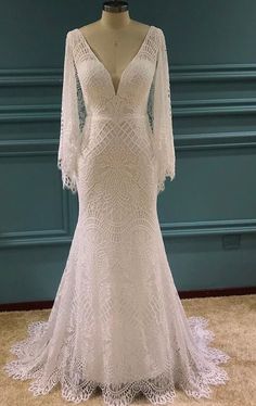 a white wedding dress on display in front of a blue wall with a mannequin