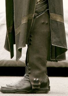 a close up of a person's foot wearing boots and a coat with buttons on it