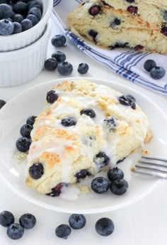 a white plate topped with blueberry scones covered in icing and toppings