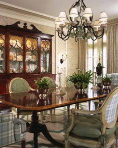 a formal dining room with chairs, table and china cabinet in the center is surrounded by potted plants