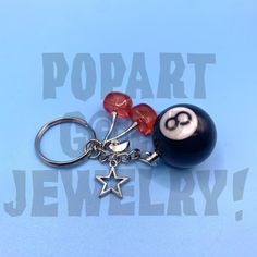 a keychain with a pool ball and star charm hanging from it's side