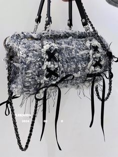 a hand holding a purse made out of crocheted yarn and leather with chains hanging from it