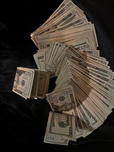 a pile of twenty dollar bills sitting on top of each other in front of a black background