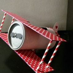 a red and white paper airplane with two straws in it's mouth on top of a black table