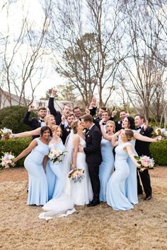 a group of people standing next to each other in front of some bushes and trees