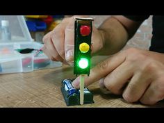 a man is making a traffic light out of legos on a table with other toys