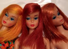 three dolls sitting next to each other on a white surface