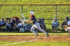 a baseball player holding a bat on top of a field with people sitting in the bleachers behind him