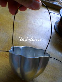 a person is holding an electric wire in front of a metal cup on a table