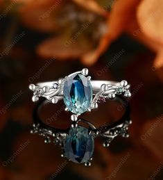 an oval blue topazte and diamond ring with leaves on the sides, surrounded by flowers