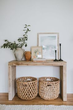 two wicker baskets sitting on top of a wooden table next to a potted plant