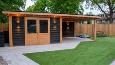 a backyard shed with grass and lights on the roof, next to a fenced in area