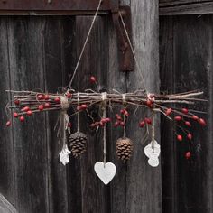 some pine cones are hanging from a branch with red berries and white hearts on it