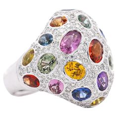 Mix Colored Sapphire, Amethyst, Garnet, Diamond Cluster Ring. This dome ring features a mixture of colors and gemstones. Each gemstone is secured in a prong setting. The ring features sapphires, amethysts, and garnet stones, which total 7.90 carats. The gemstones are multi-colored. The ring is decorated with numerous additional round-cut diamonds, totaling 1.41 carats. Sized at USA 6.5, this is an ideal unisex statement piece. Item Details: - Type: Ring - Metal: 18K White Gold - Weight: 13.10 grams - Setting: Bezel - Size: 6.5 _______________________ Main Stone Details: - Type: Sapphire, Amethyst, Garnet - Carat: 7.90 CTTW - Cut: Multi Cut - Color: Green, Red, Orange, Yellow, Blue, Purple _______________________ Side Stone Details:  - Type: Diamond - Carat: 1.41 CTTW - Cut: Round - Quantit Multi Stone Ring 1stdibs, Dome Ring, Garnet Stone, Domed Ring, Diamond Cluster Ring, Diamond Cluster, Cluster Ring, Round Cut Diamond, Cut And Color