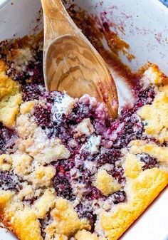 blueberry cobbler in a white dish with a wooden spoon resting on the top