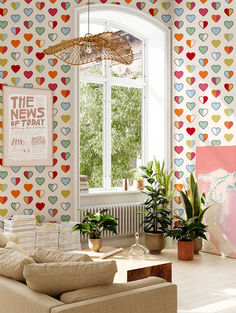 a living room filled with furniture next to a window covered in colorful hearts wallpaper