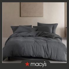 an image of a bed with grey sheets and pillows