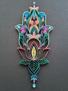 an intricately designed brooch with flowers and leaves on the front, sitting on a black surface