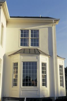 a large white house with three windows on the front and one window in the back