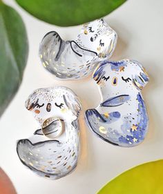 three ceramic animal figurines sitting on top of a white table next to green leaves