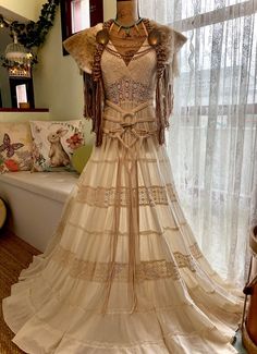 a dress on display in front of a window with sheer curtains and lace trims