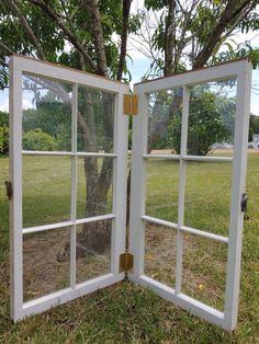 an open window sitting in the grass next to a tree