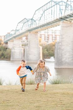 two young children running in front of a bridge