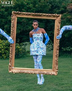 a woman standing in front of a mirror with her hands on her hips and wearing blue tights