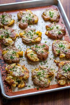 a pan filled with cooked potatoes covered in parmesan cheese and seasoning sprinkles