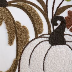 a close up of a decorative pumpkin on a white surface with brown and green accents